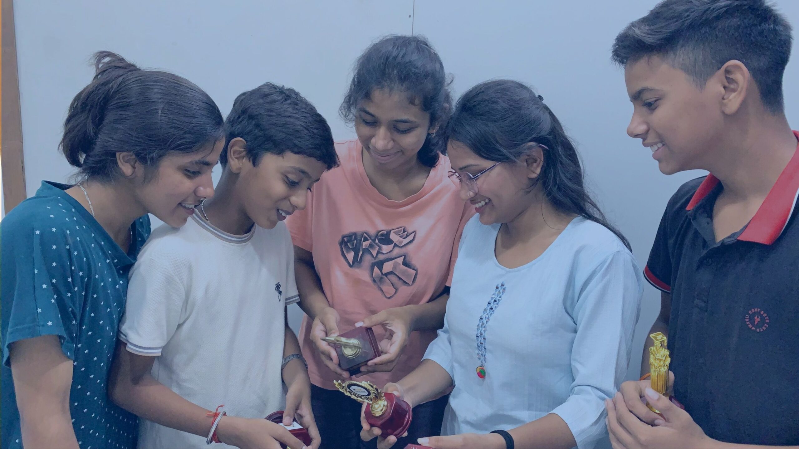 Students at AIM English holding trophies they won by participating in various competitions