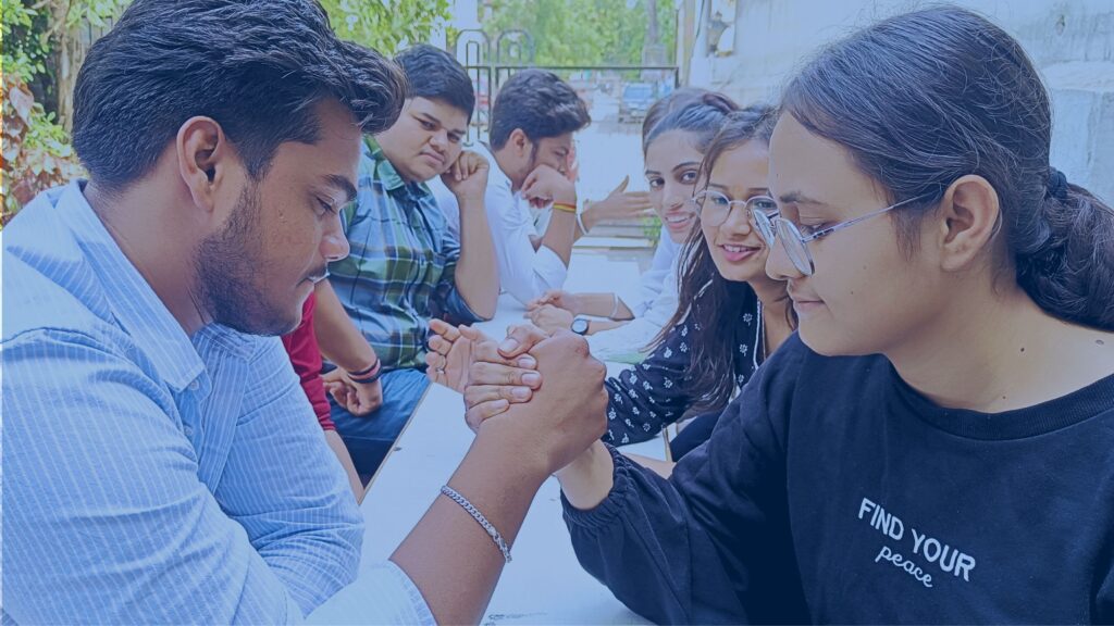 Students at AIM English sitting in two groups and enjoying an arm wrestling activity