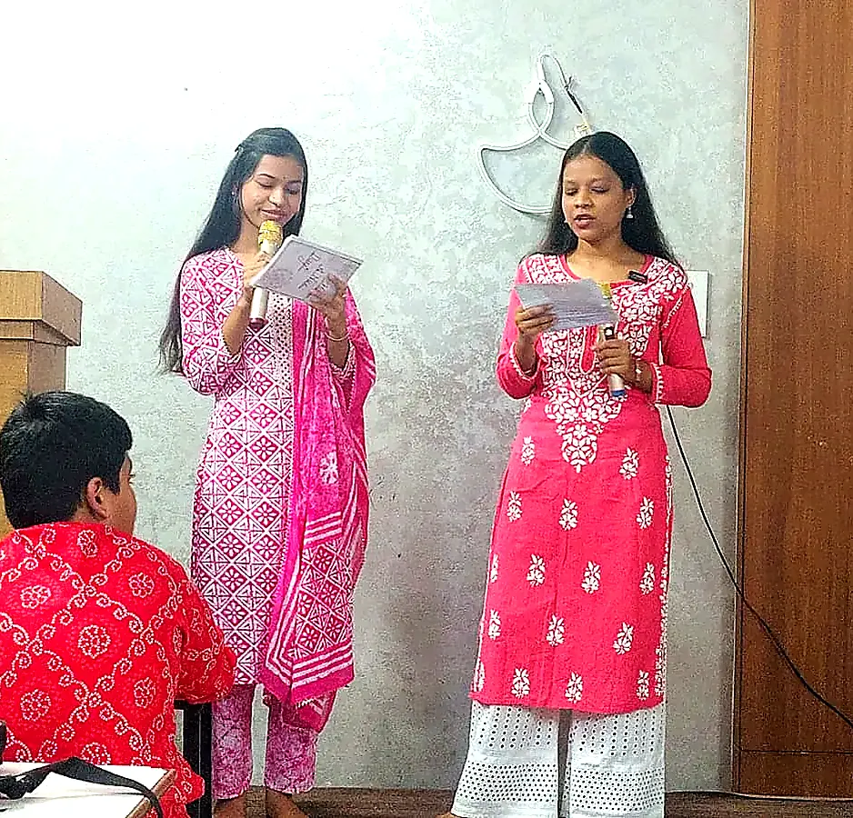 Two students delivering a presentation with a microphone during stage speaking practice at AIM English Raipur
